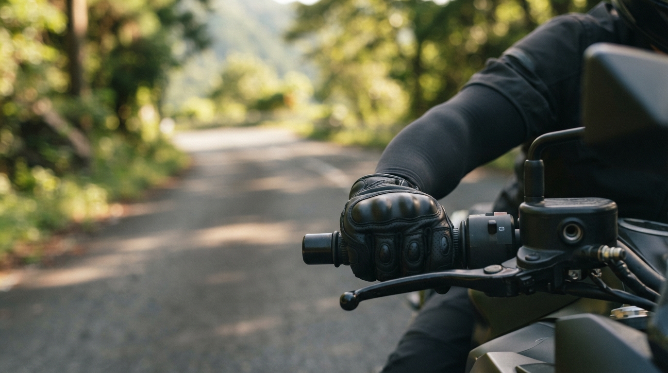 バイクのハンドルを握る腕に黒い冷感アームカバーを装着した男性の手元アップ